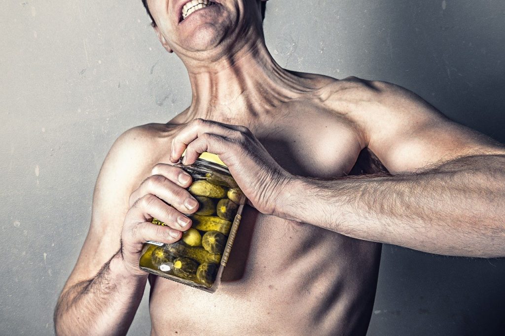 man struggles to open pickle jar