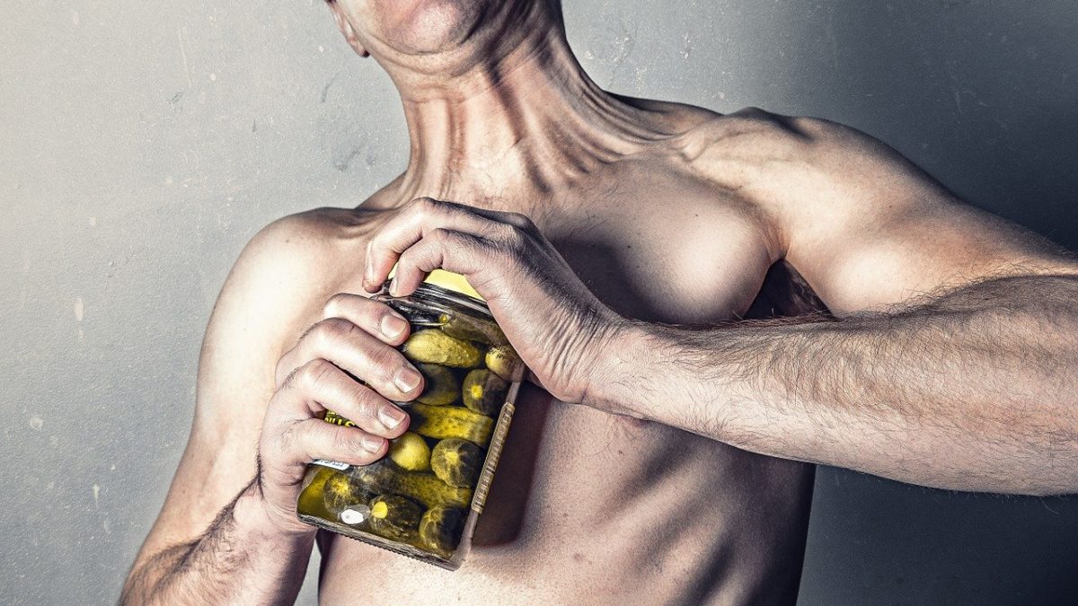 man struggles to open pickle jar