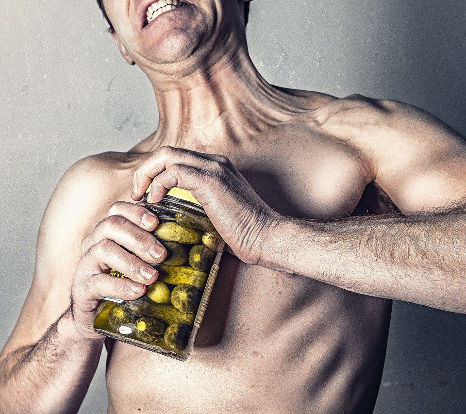 man struggles to open pickle jar