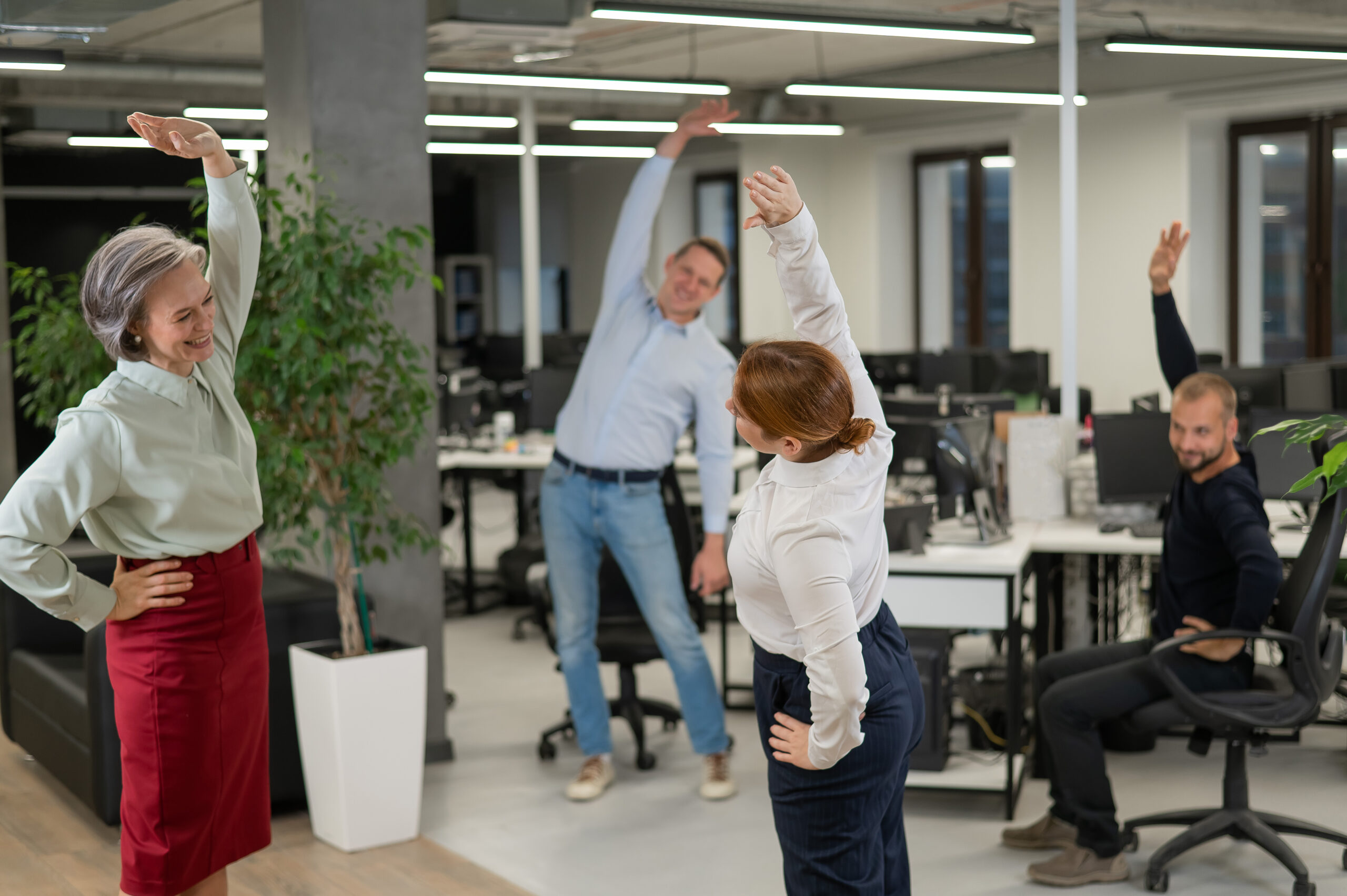 Four office workers warm up during a break. Employees do fitness exercises at the workplace