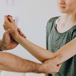 crop-unrecognizable-chiropractor-examining-arm-of-smiling-4506071_opt