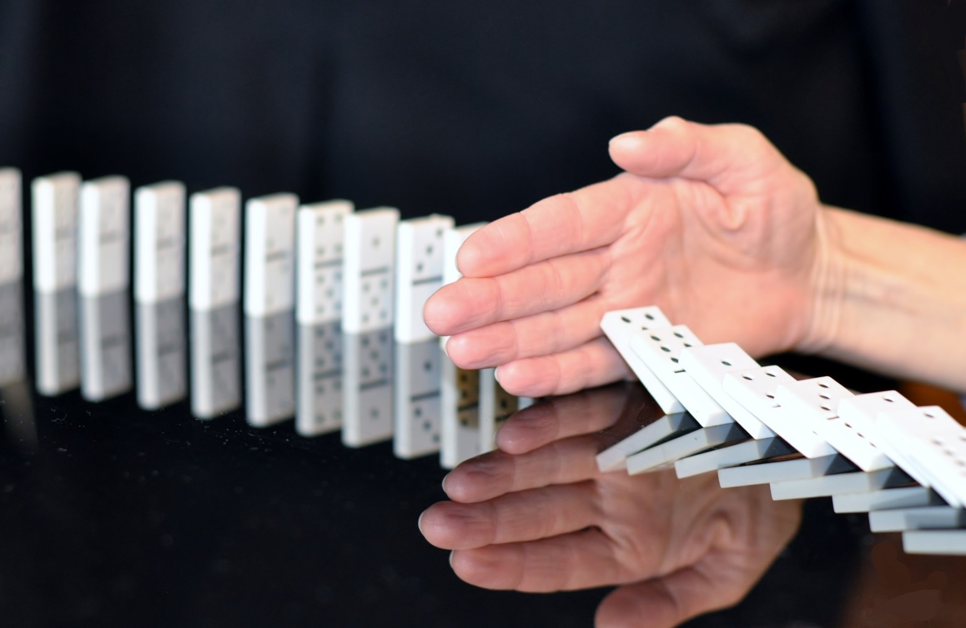 Hand stopping dominoes from falling