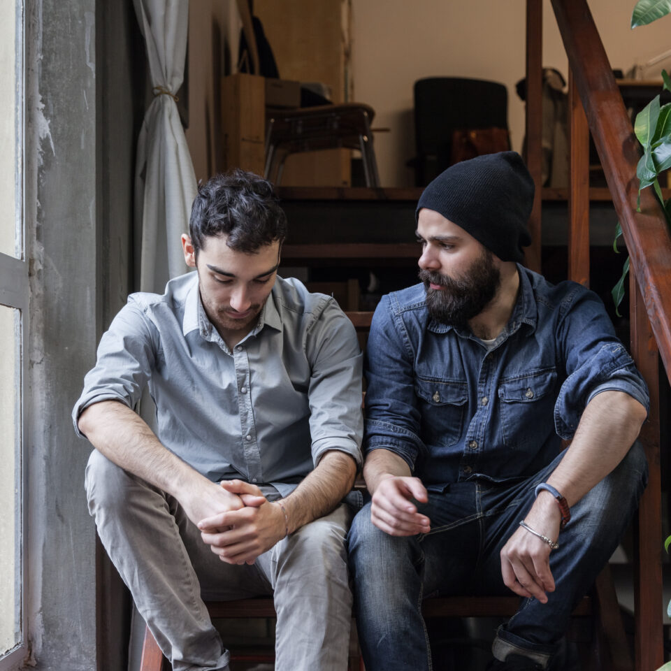 Couple of young men talking on the stairs of an office.