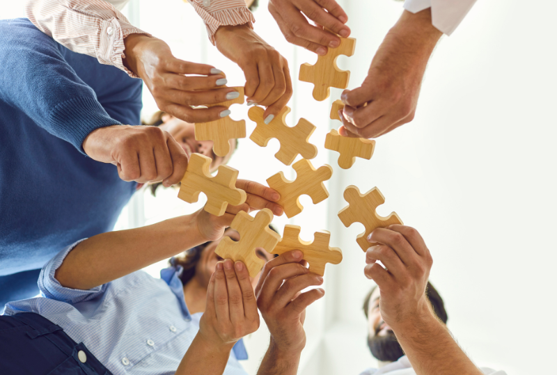 Image of a group of people holding puzzle pieces together