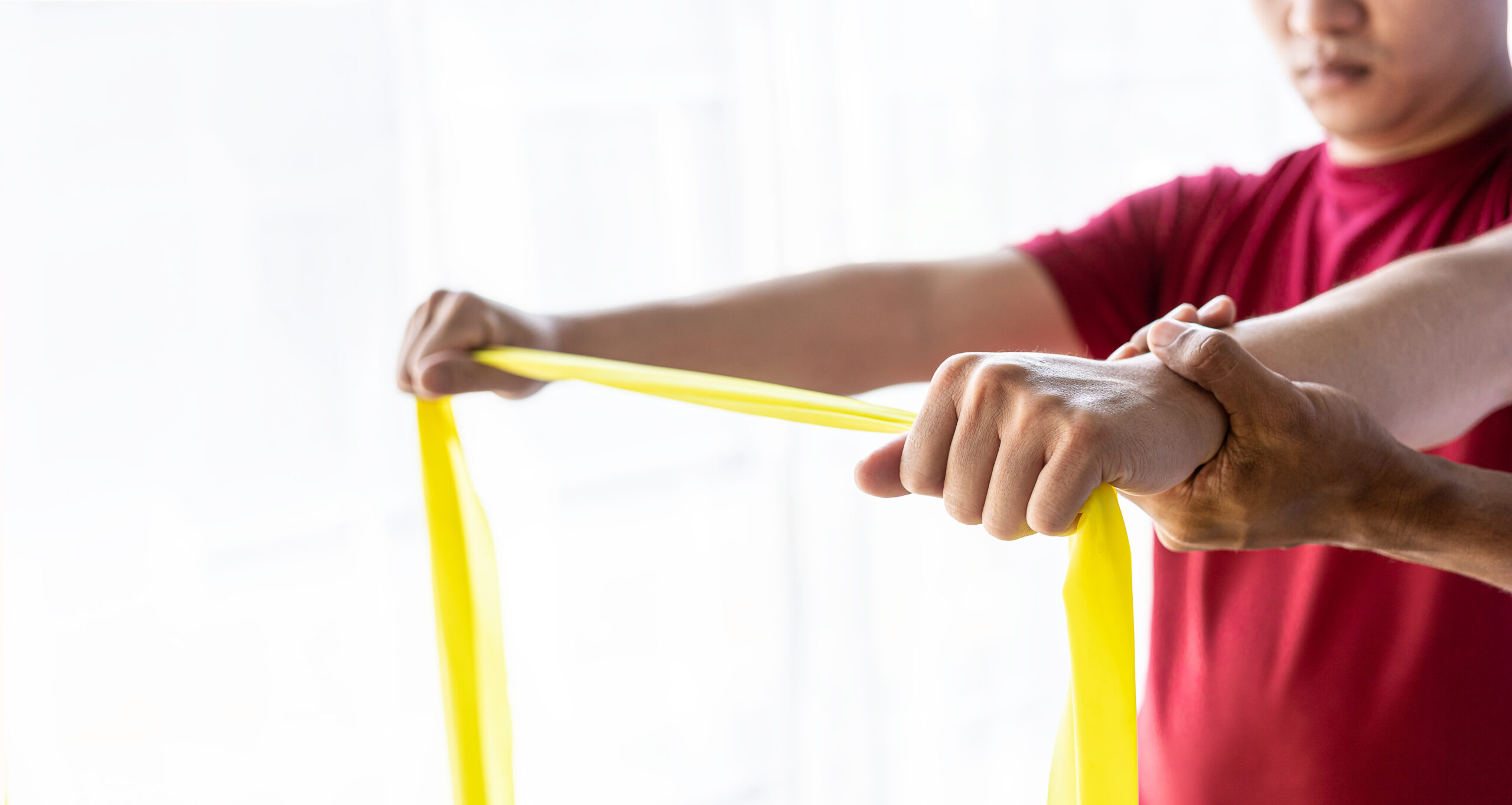 Young male doing shoulder rehabilitation with stretch band, onsite workplace health