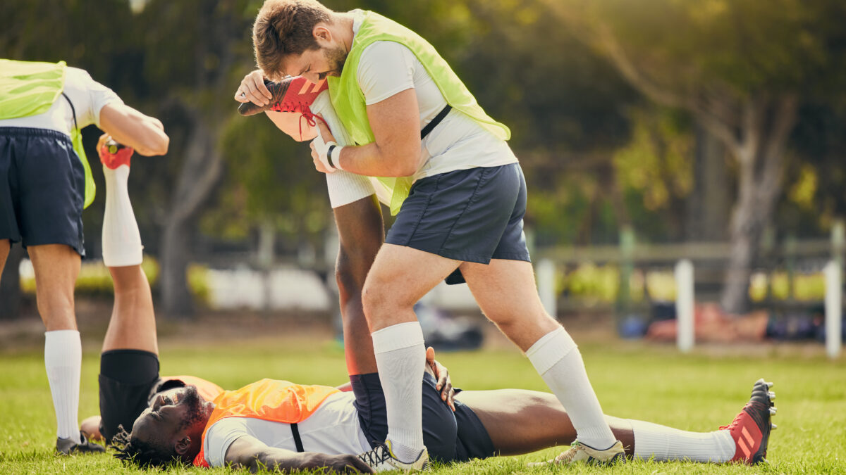 Rugby sports, men training and stretching outdoor on grass field with team warm up for legs. Athlete group together for fitness, exercise and workout for professional sport with coach and teamwork.