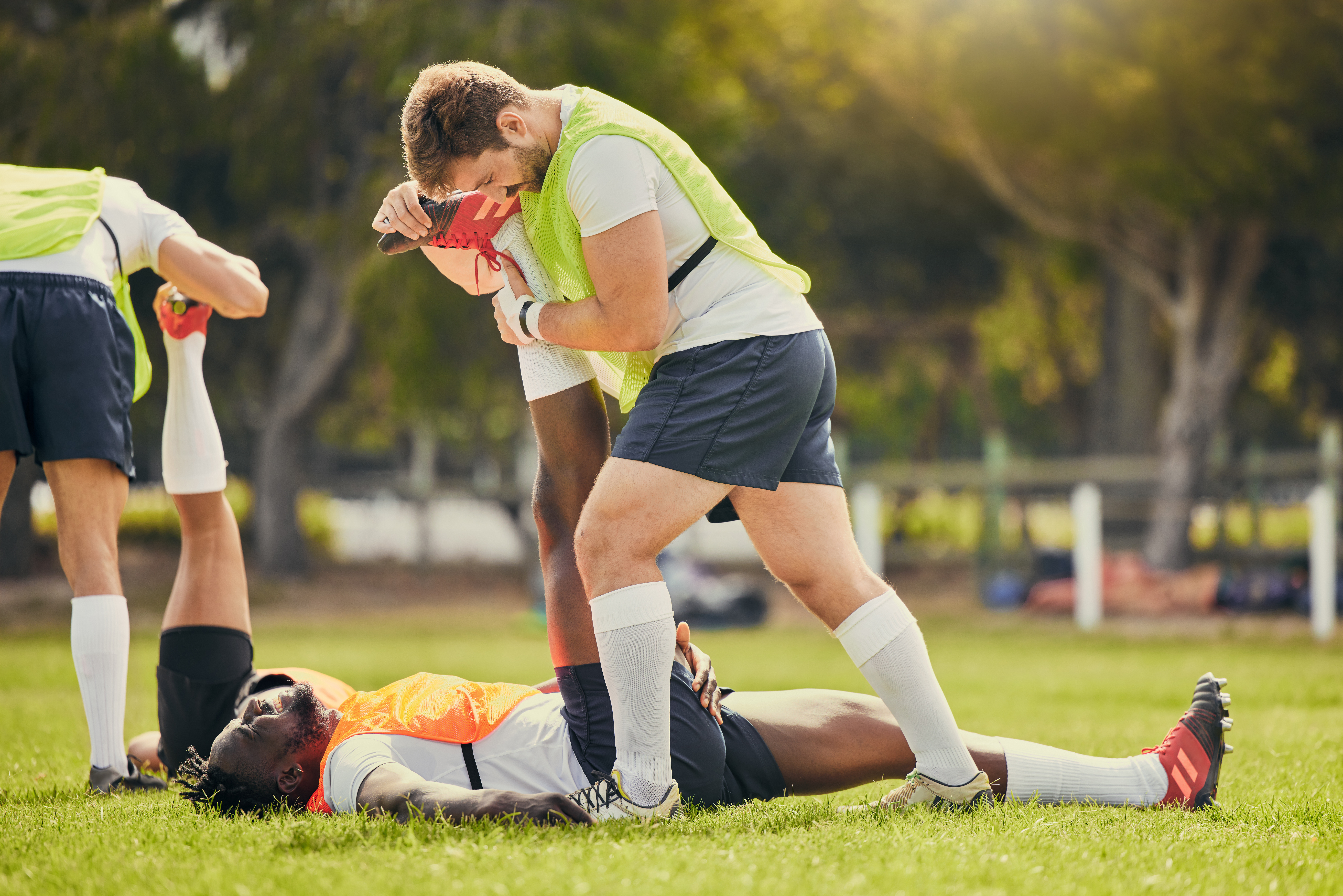 Rugby sports, men training and stretching outdoor on grass field with team warm up for legs. Athlete group together for fitness, exercise and workout for professional sport with coach and teamwork.