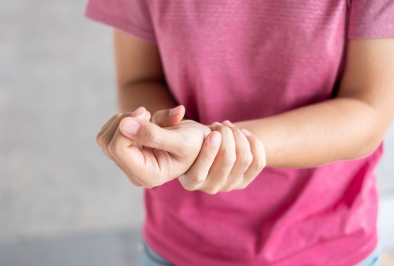 Young woman holding her wrist in pain because of Intersection Symptom.