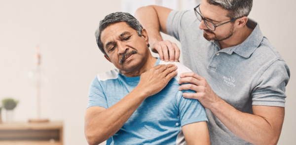A physio, chiro, osteo is treating a male worker's shoulder.